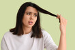 Young woman with hair loss problem on green background