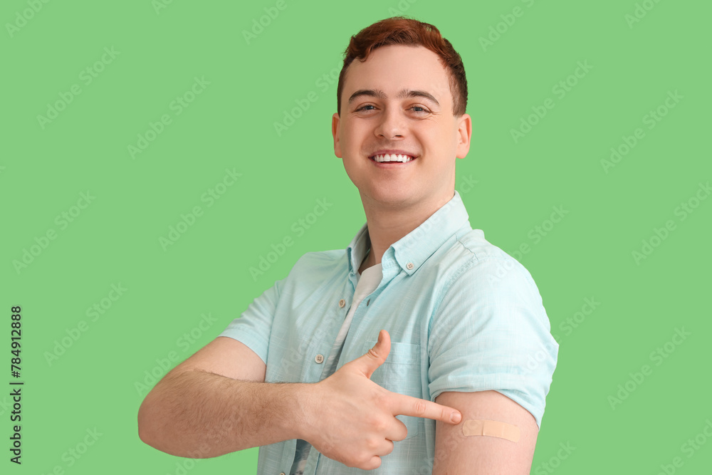 Young man with applied medical patch on green background. Vaccination concept