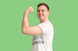 Young man showing strength symbol with applied medical patch on green background. Vaccination concept