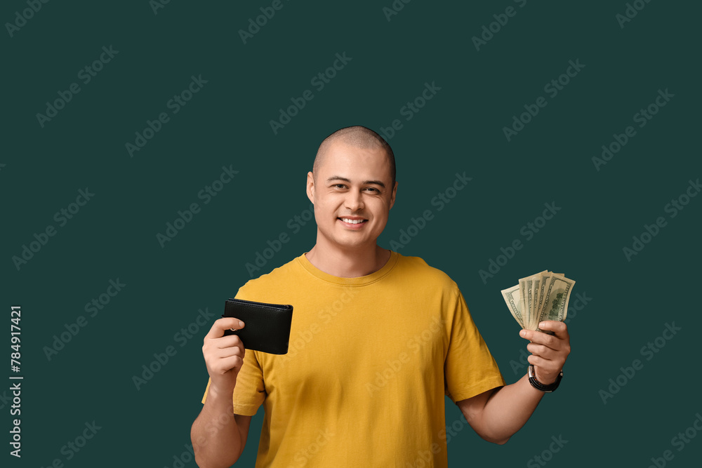Young man with wallet and money on green background