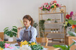 Floristry concept, Woman florist looking on smartphone and thinking design bouquet in flower shop