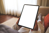 Fototapeta  - Mockup image of a woman holding digital tablet with blank desktop screen while sitting on a sofa at home