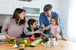 © Graphicroyalty - Overjoyed young family with son and daughter have fun cooking diner or lunch at home together, happy smiling parents enjoy weekend play with small children doing cooking in kitchen
