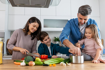 Wall Mural - Family with adorable son and daughters gathered in modern kitchen cooking together. Enjoy communication and cookery hobby concept.