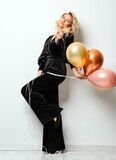 Fototapeta  - Beautiful Woman with Balloons over White background. Birthday Party Time. Fashion Model with Curly Hairstyle in Black Long Dress