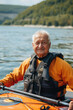 An older man is sitting in a kayak on a lake, wearing a life jacket
