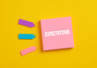 Expectations in business or education. The word expectations on pink note paper.