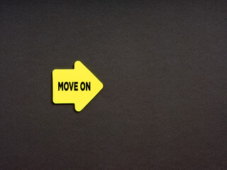 Wall Mural - Motivational concept for improvement in business or career. Yellow arrow shaped sticker with the word move on on black background.