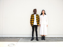 Man And Woman Leaning Against Blank Wall Next To Each Other