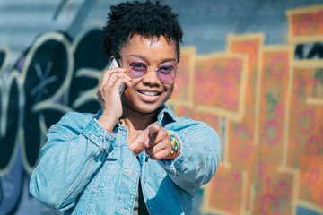 Wall Mural - african american woman using phone on the street and pointing