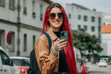 Wall Mural - young tourist woman with backpack with leather jacket and phone on the street