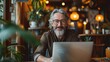© PaulShlykov - Freelance In Older Age. Happy Senior Man Sitting At Desk With Laptop. Happy middle aged man, entrepreneur, small business owner working online.