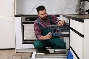 Poster - Serviceman repairing dishwasher cutlery rack in kitchen