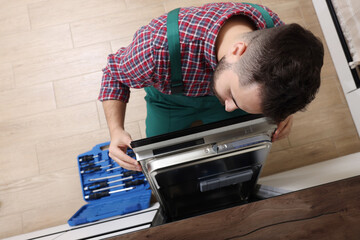 Sticker - Serviceman examining dishwasher's door indoors, above view