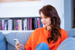 Smiling brunette haired woman using her smartphone and home