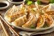  A plate of authentic Japanese gyoza potsticker appetizers with dipping sauce and chopsticks, against a wooden background