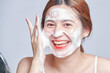 © nareekarn - Smiling young woman washing foam face by natural foamy gel. satisfied girl with bare shoulders applying cleansing beauty product on cheeks. personal hygiene, skincare daily routine.