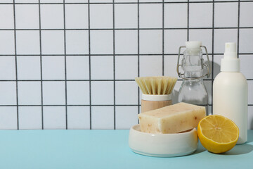 Wall Mural - Soap, lemon, brush and bottles on table on light background, space for text