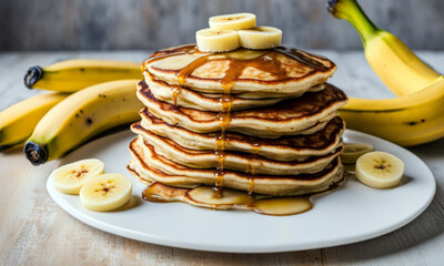 Wall Mural - Stack of homemade banana pancakes with sliced bananas and maple syrup on a white plate