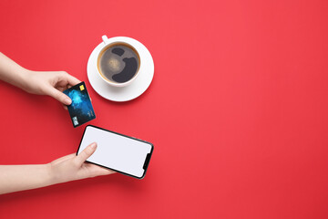 Canvas Print - Online payment. Woman with smartphone, credit card and coffee on red background, top view. Space for text