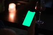hand hold green screen phone in dark bar at night