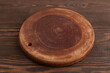 Empty round wooden cutting board on brown wooden. Side view