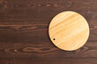 Empty round wooden cutting board on brown wooden. Top view, copy space