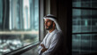 A Confident Arab Businessman Wearing UAE Emirati Traditional Dress, White kandura, standing in a daylight next to a window, Arabian man in the Emirates, generative ai.