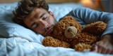 Fototapeta Sport - A tired handsome man in pajamas lies in bed with a teddy bear.