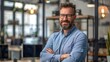 © ckybe - Content male business owner standing with arms folded in his workplace.