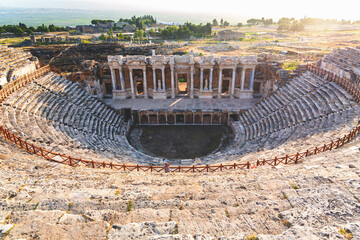 Wall Mural - Hierapolis ancient theatre panoramic view against sun light. Golden hour. Pamukkale, Denizli, Turkey (Turkiye)