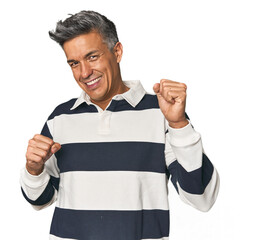 Middle-aged Latino man celebrating a special day, jumps and raise arms with energy.