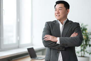 Canvas Print - Portrait of smiling businessman with crossed arms in office. Space for text