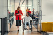 © .shock - A business leader with her colleague, an African-American businessman who is a disabled person, pass by their colleagues who work in modern offices