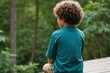 © ThomasLENNE - back view of boy with curly hair playing on wooden platform