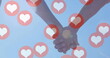 Image of red heart icons floating over mid section of couple in love holding hands
