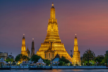 Wat Arun stupa, a significant landmark of Bangkok, Thailand, stands prominently along the Chao Phraya River, with a beautiful twilight.