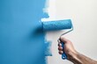 © Alina - Male hand holding roller brush with blue paint on the wall