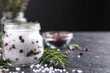 Salt with fresh rosemary and peppercorns on dark grey textured table, closeup. Space for text