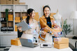 Small business entrepreneur SME freelance Asian businesswoman and woman working BOX, tablet and laptop online, marketing, packaging, delivery. ..