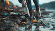 A volunteer collects garbage on a muddy beach. Close up