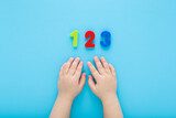 Fototapeta Tulipany - Baby boy hands and colorful 123 numbers on light blue table background. Pastel color. Time to learning. Closeup. Point of view shot. Top down view.