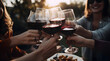 Friends clinking their glasses of red wine while enjoying an outdoor autumn celebration, with a table full of delicious foods and snacks nearby.