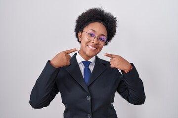 Canvas Print - Beautiful african woman with curly hair wearing business jacket and glasses smiling cheerful showing and pointing with fingers teeth and mouth. dental health concept.