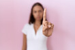 Young hispanic woman wearing casual white t shirt pointing with finger up and angry expression, showing no gesture