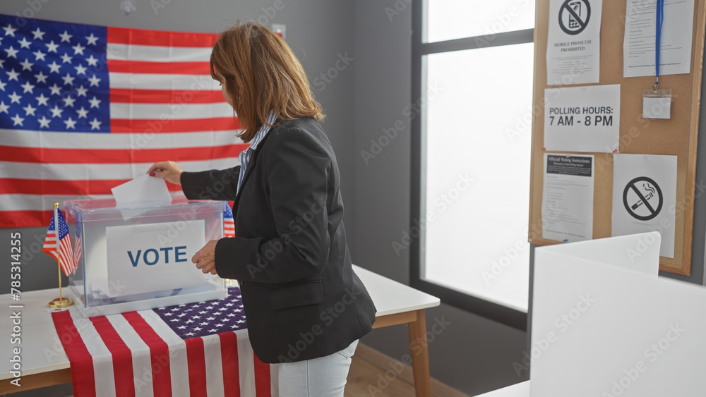 Mature woman voting in an american election booth with the us flag in ...