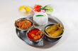 Bengali non vegetarian food thali comprising of plain white rice with spicy chicken curry, prawn and fish dishes, along with dessert and salad