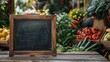 Empty chalkboard on table with fresh healthy vegetables in the background. Farmers market, regional bio organic shop, vegan food concept