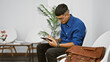 © Krakenimages.com - In the hustle of a buzzing waiting room, a young latin man, a vision of professionalism, plunges deep into thought, pen poised on clipboard as he meticulously documents crucial details