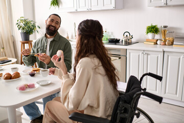 cheerful woman with inclusivity in wheelchair eating sweets at breakfast with her handsome husband